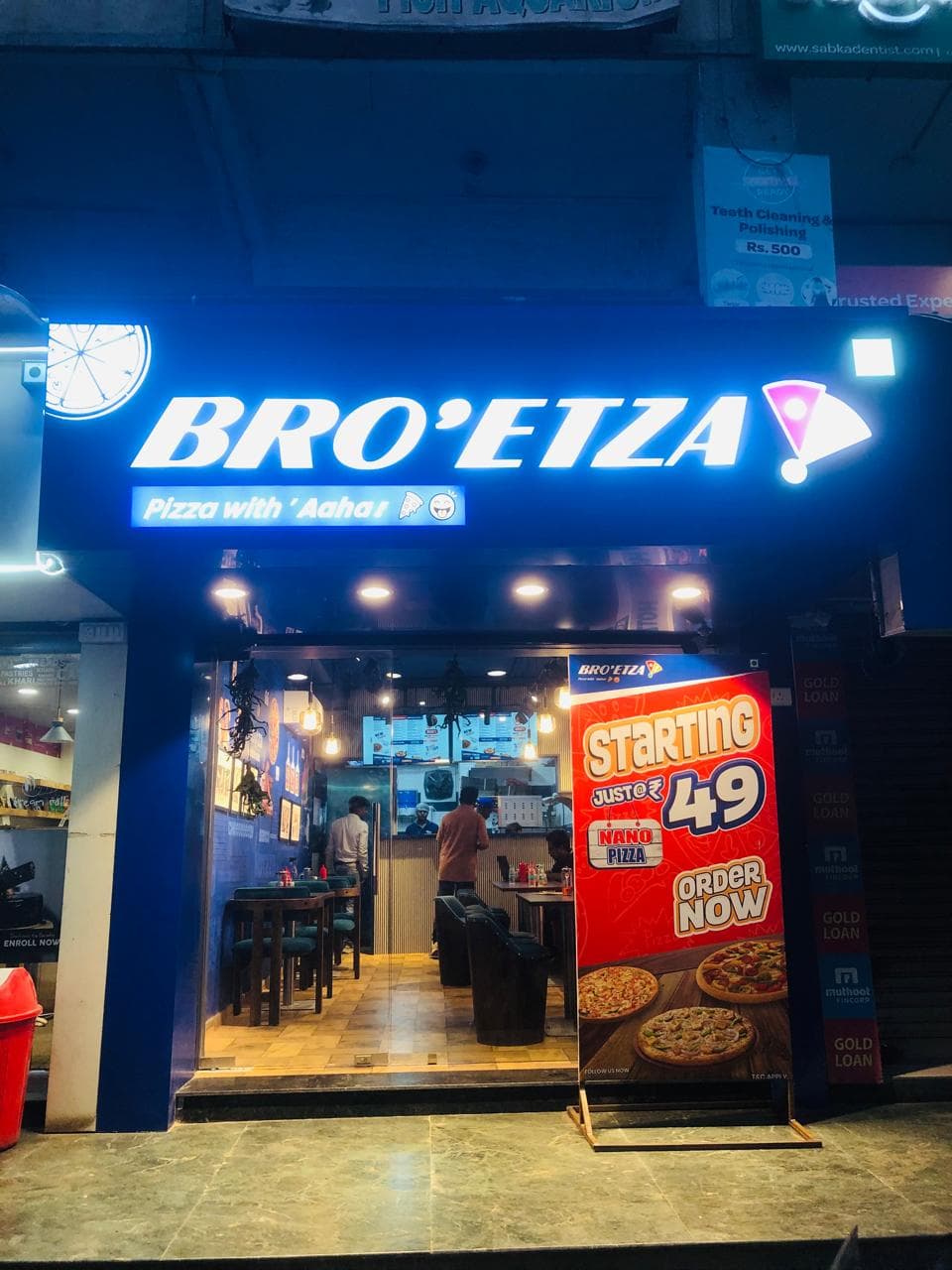 Bro'etza outlet at night with its illuminated blue 'Pizza with Aaha!' signage